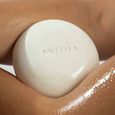 White soap bar with 'MUTHA' branding on a person's skin