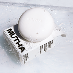Stylish image of the Nudist Exfoliating Body Bar on top of its box with splashing water