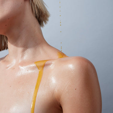 Stylish image of the Body Oil dripping onto a model's shoulder and pooling in the collarbone , 25ml / 0.8 fl oz , 100ml / 3.4 fl oz
