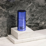 Image of the Body Contour Serum standing on marble blocks against a marble background