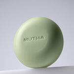 Aesthetic hero shot of the Detox Greens Exfoliating Body Bar balanced on a white architectural riser.